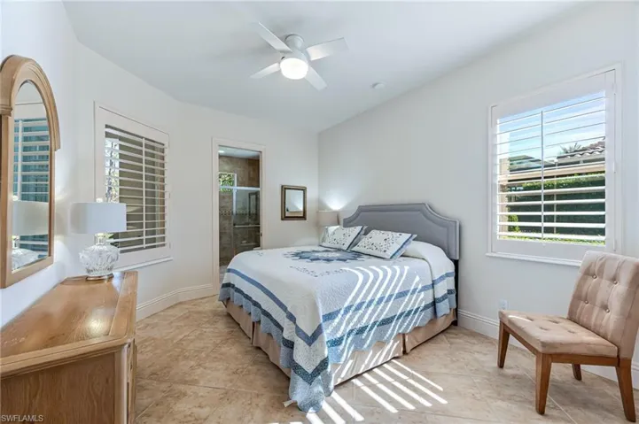 Bedroom with light tile patterned flooring, ceiling fan, and ensuite bath
