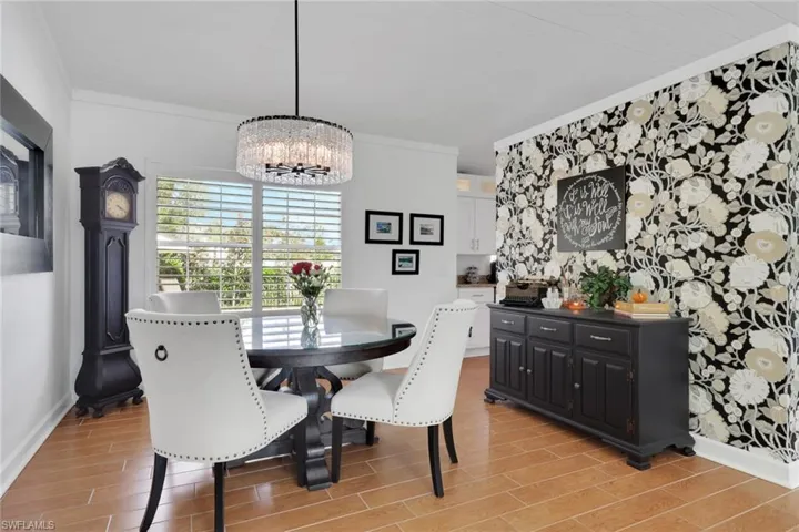 Dining room with wood tiled floors, ornamental molding, and a chandelier