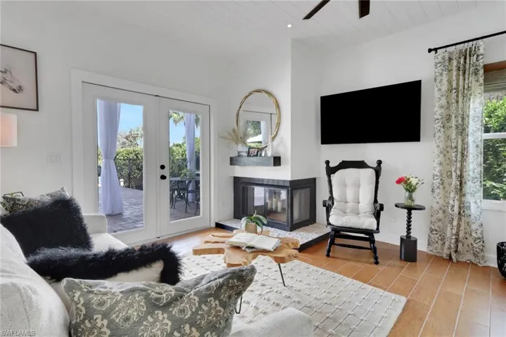 Kitchen featuring white cabinetry with upgraded upper cabinetry that has accent lighting, granite countertops, tongue & groove ceiling, ceramic tile flooring, overlooking a beautiful outdoor sanctuary.