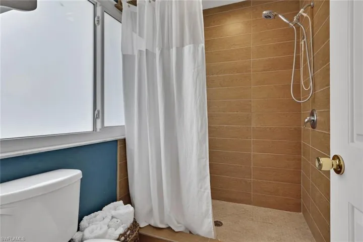 Full bathroom with double vanity, curtained shower, and light tile patterned flooring