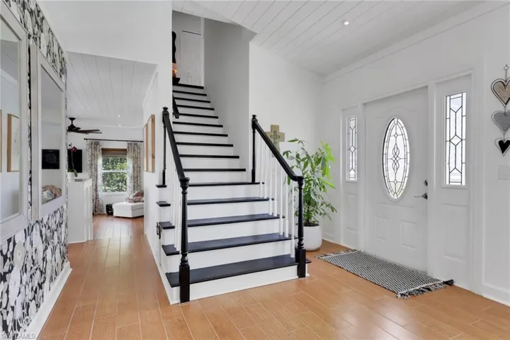 Entryway featuring plenty of natural light, recently painted stairs, tongue & groove ceiling, baseboards & crown moldingl.