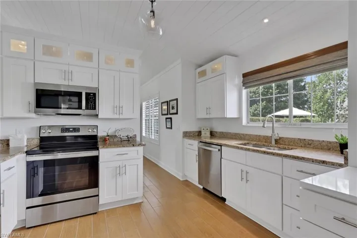Family room featuring ceramic wood floors, a multi sided real log burning fireplace, hurricane impact French door, ceiling fan, & tong & groove ceiling.