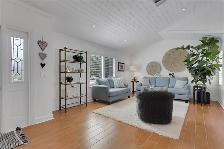 Living room with ceramic wood finished floors, tong & groove ceiling, recessed lighting and new plantation shutters