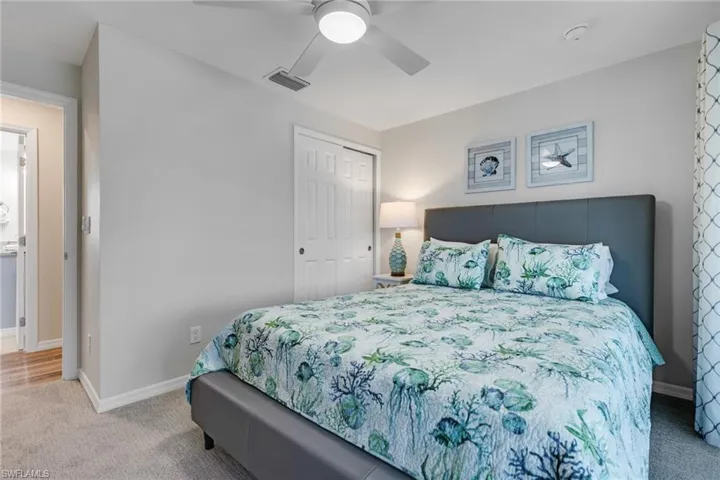 Carpeted bedroom with ceiling fan and a closet