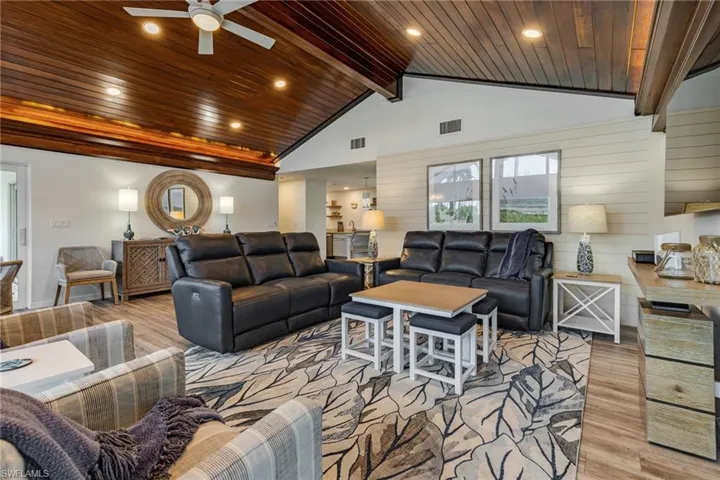 Living room featuring beamed ceiling, ceiling fan, wooden ceiling, and light hardwood / wood-style flooring