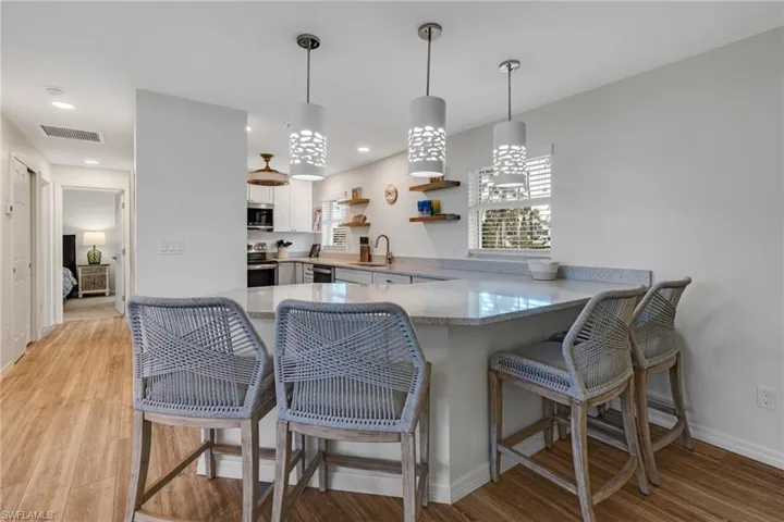 Kitchen featuring kitchen peninsula, appliances with stainless steel finishes, a breakfast bar, and white cabinetry