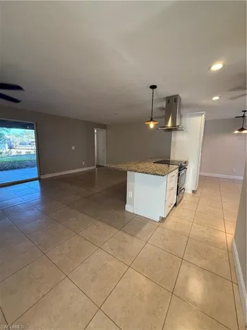 Kitchen featuring dark stone counters, decorative light fixtures, extractor fan, range, and light tile patterned floors