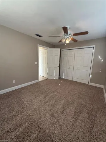 Unfurnished bedroom with carpet flooring, a closet, and a ceiling fan