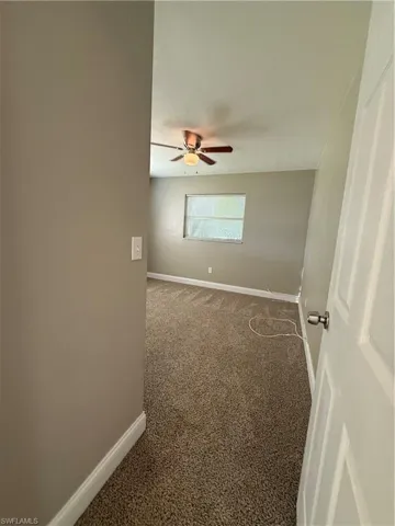 Carpeted empty room with baseboards and ceiling fan