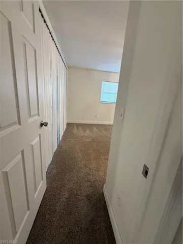 Corridor with dark carpet and baseboards
