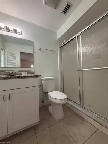 Bathroom with a stall shower, vanity, and light tile patterned floors