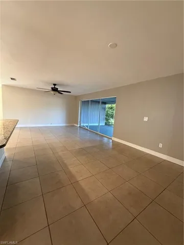 Empty room with ceiling fan and light tile patterned floors