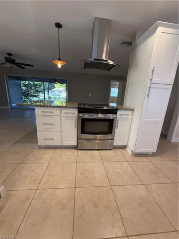 Kitchen with white cabinets, stainless steel range with electric stovetop, range hood, and decorative light fixtures