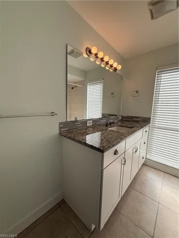 Bathroom featuring vanity, light tile patterned floors, and a tile shower