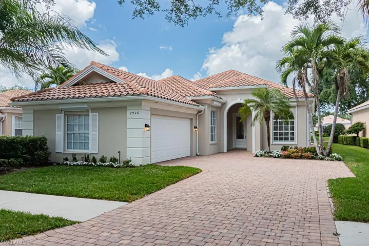 Mediterranean / spanish home with a tiled roof, an attached garage, stucco siding, a front lawn, and driveway