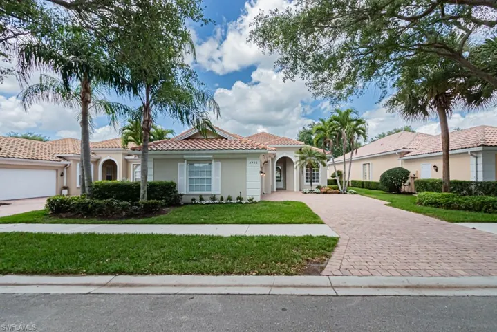 Mediterranean / spanish-style house with a tiled roof, a front lawn, driveway, and stucco siding