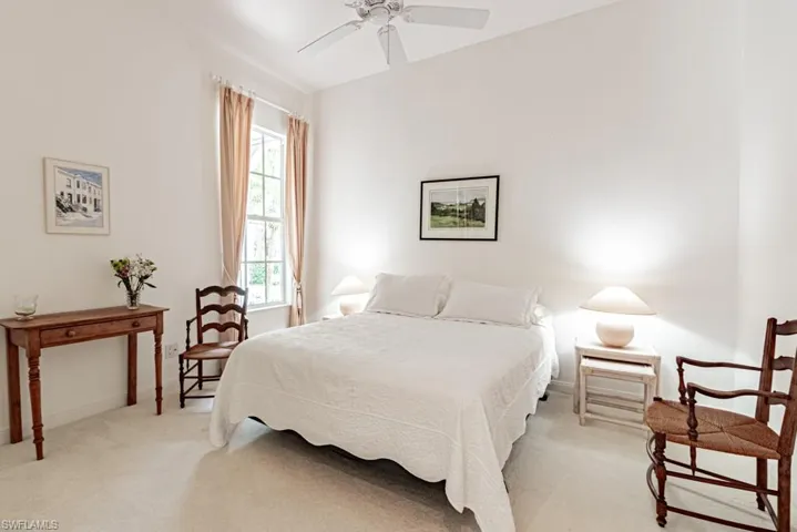 Bedroom with ceiling fan, light colored carpet, and baseboards