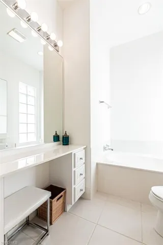 Bathroom with tile patterned flooring, vanity, a garden tub, and toilet