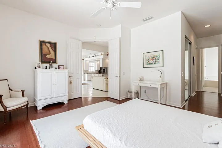Bedroom with baseboards, recessed lighting, ensuite bath, visible vents, and wood finished floors