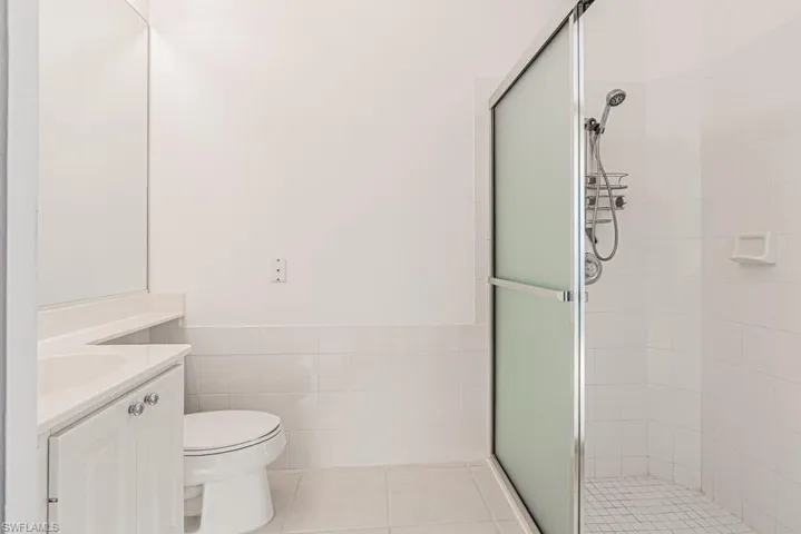 Full bathroom featuring tile patterned flooring, tile walls, a stall shower, and vanity