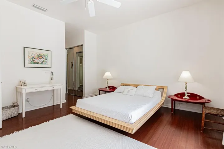 Bedroom featuring baseboards, wood-type flooring, a ceiling fan, and visible vents