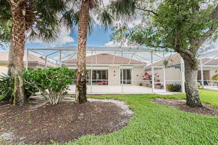 Back of property featuring a patio, stucco siding, a lanai, a tiled roof, and a lawn