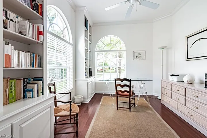 Living area featuring crown molding, ceiling fan, baseboards, and dark wood finished floors