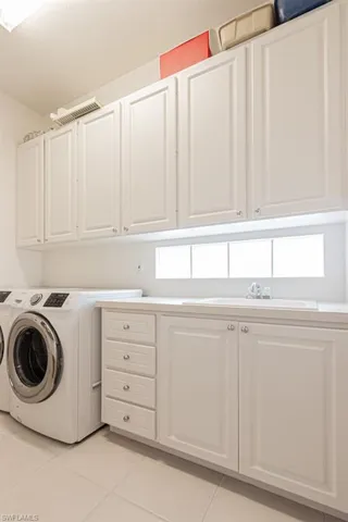 Laundry area with washer and dryer, a sink, light tile patterned flooring, and cabinet space
