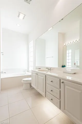 Bathroom featuring visible vents, toilet, vanity, tile patterned floors, and a garden tub