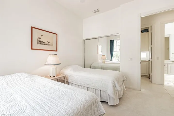 Bedroom with a closet, light carpet, light tile patterned floors, ensuite bath, and ceiling fan