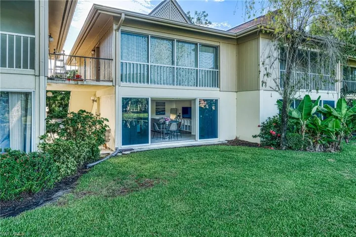 Back of property featuring a lawn and stucco siding