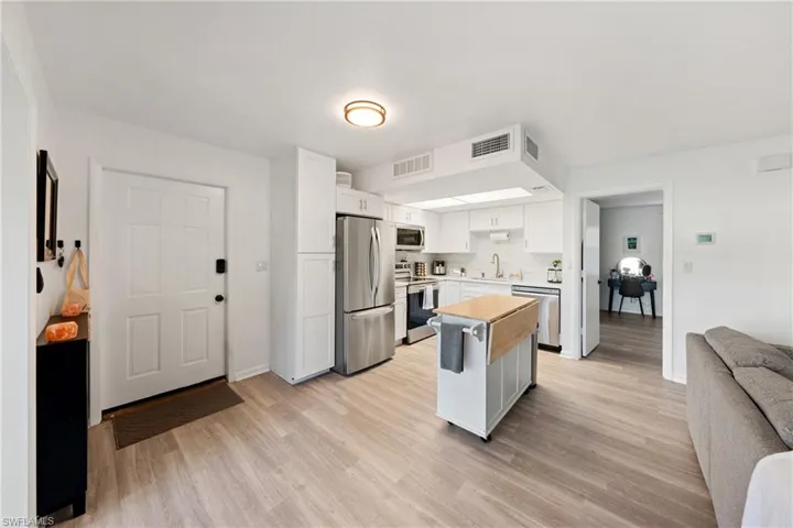 Kitchen featuring appliances with stainless steel finishes, light wood finished floors, white cabinets, and open floor plan