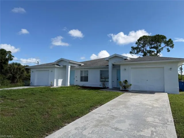 Contemporary architecture with a light exterior finish, featuring two single-car garages, a concrete driveway, and a covered entry
