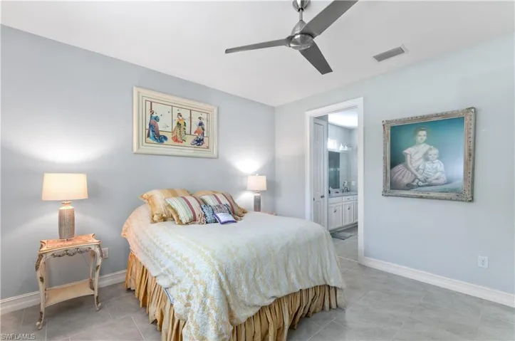 Tiled bedroom featuring ensuite bathroom and ceiling fan
