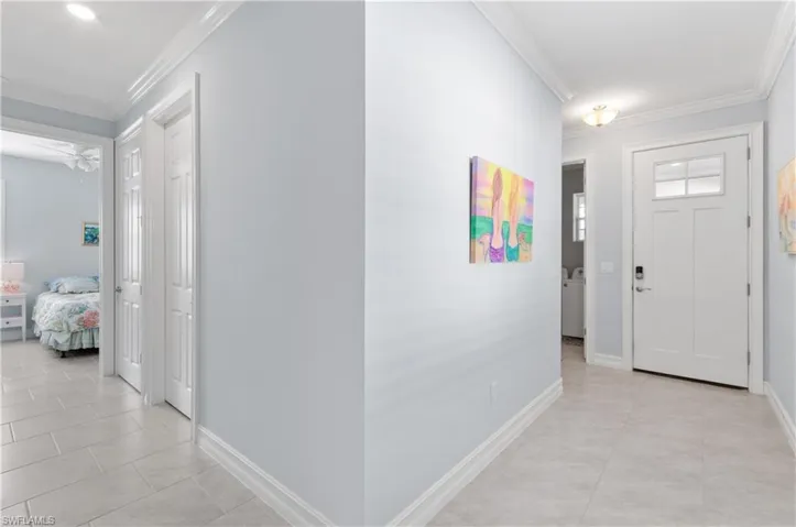 Tiled foyer entrance featuring ceiling fan and ornamental molding