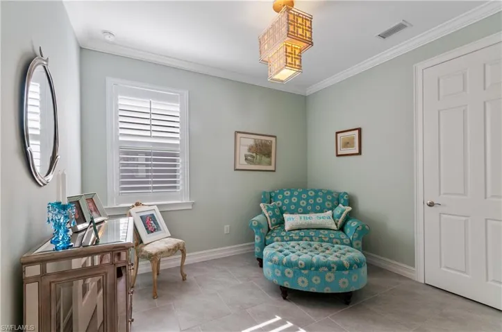 Den or bedroom with light tile patterned flooring and crown molding