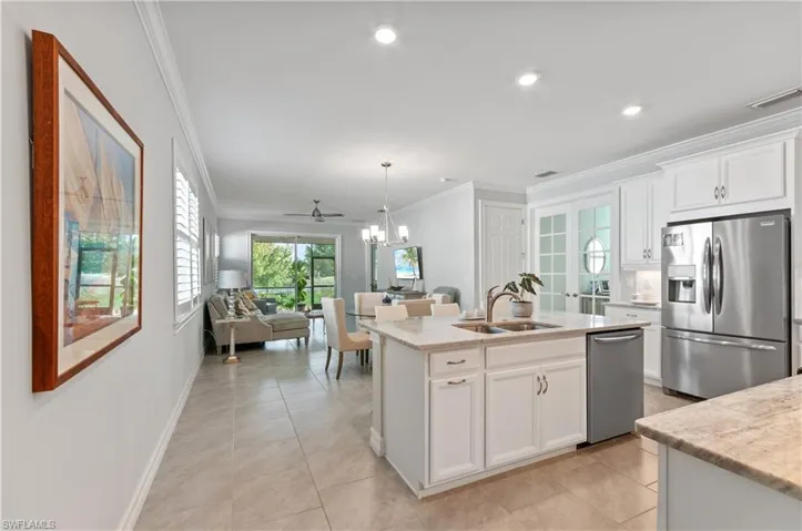 Kitchen featuring a kitchen island with sink, white cabinetry, light tile patterned flooring, and stainless steel appliances