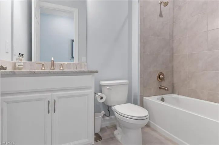 Full bathroom featuring vanity, tiled shower / bath combo, toilet, and tile patterned flooring