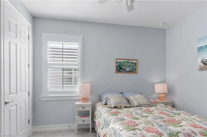 Bedroom with a closet, light tile patterned floors, and ceiling fan