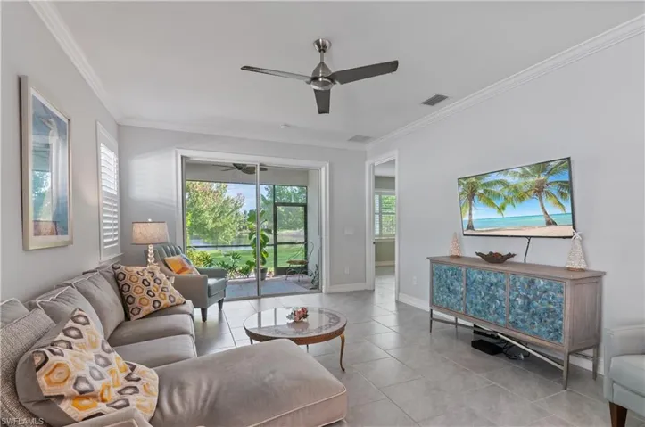 Living room featuring ornamental molding, light tile patterned floors, and ceiling fan