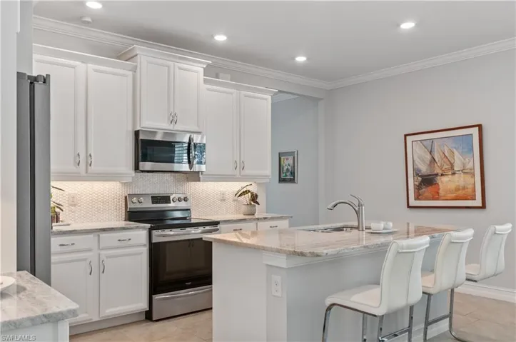 Kitchen featuring tasteful backsplash, light stone countertops, appliances with stainless steel finishes, and light tile patterned floors