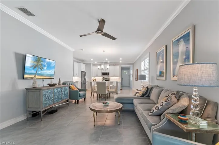Living room featuring crown molding, ceiling fan, and light tile patterned floors