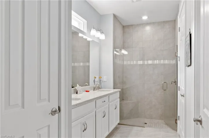 Master bathroom featuring dual vanity, walk in shower, and tile patterned flooring