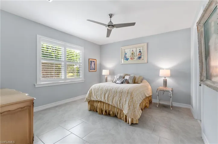 Tiled bedroom featuring ceiling fan