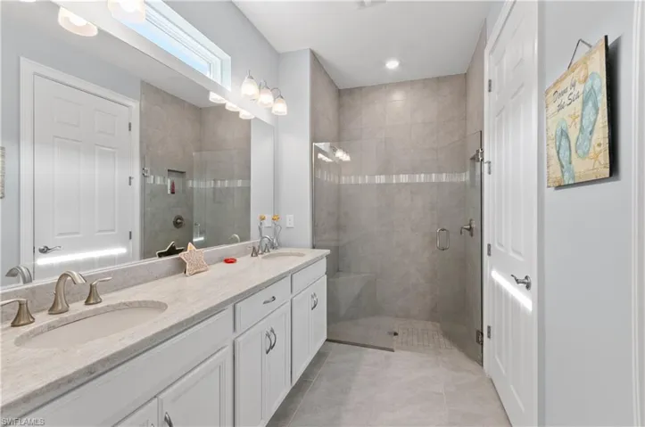 Master bathroom featuring a shower with shower door, tile patterned floors, and double sink vanity