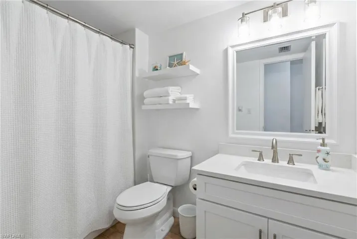 Full bath with a shower with shower curtain, vanity, and light tile patterned flooring