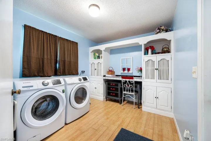 Laundry area with a textured ceiling, light wood-type flooring, and washer and dryer