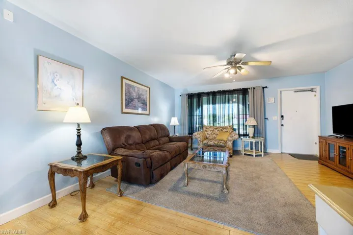 Living area with light wood-style floors and a ceiling fan