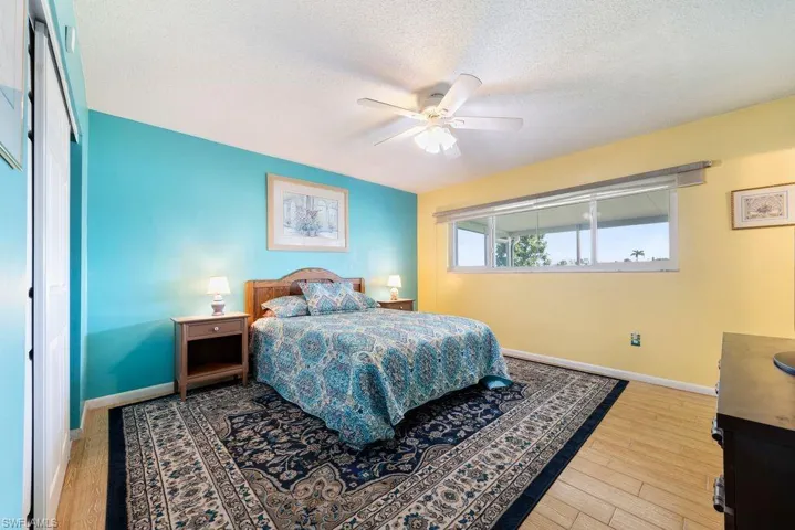 Bedroom featuring light wood-type flooring, a ceiling fan, a textured ceiling, and a closet