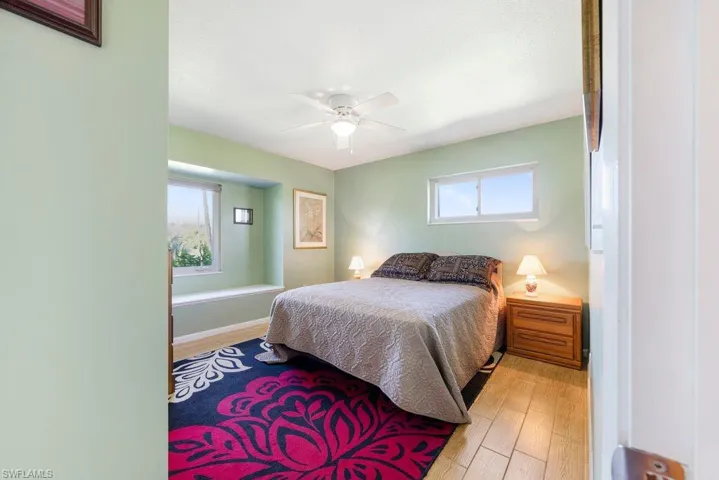 Bedroom featuring light wood-style flooring, multiple windows, and a ceiling fan